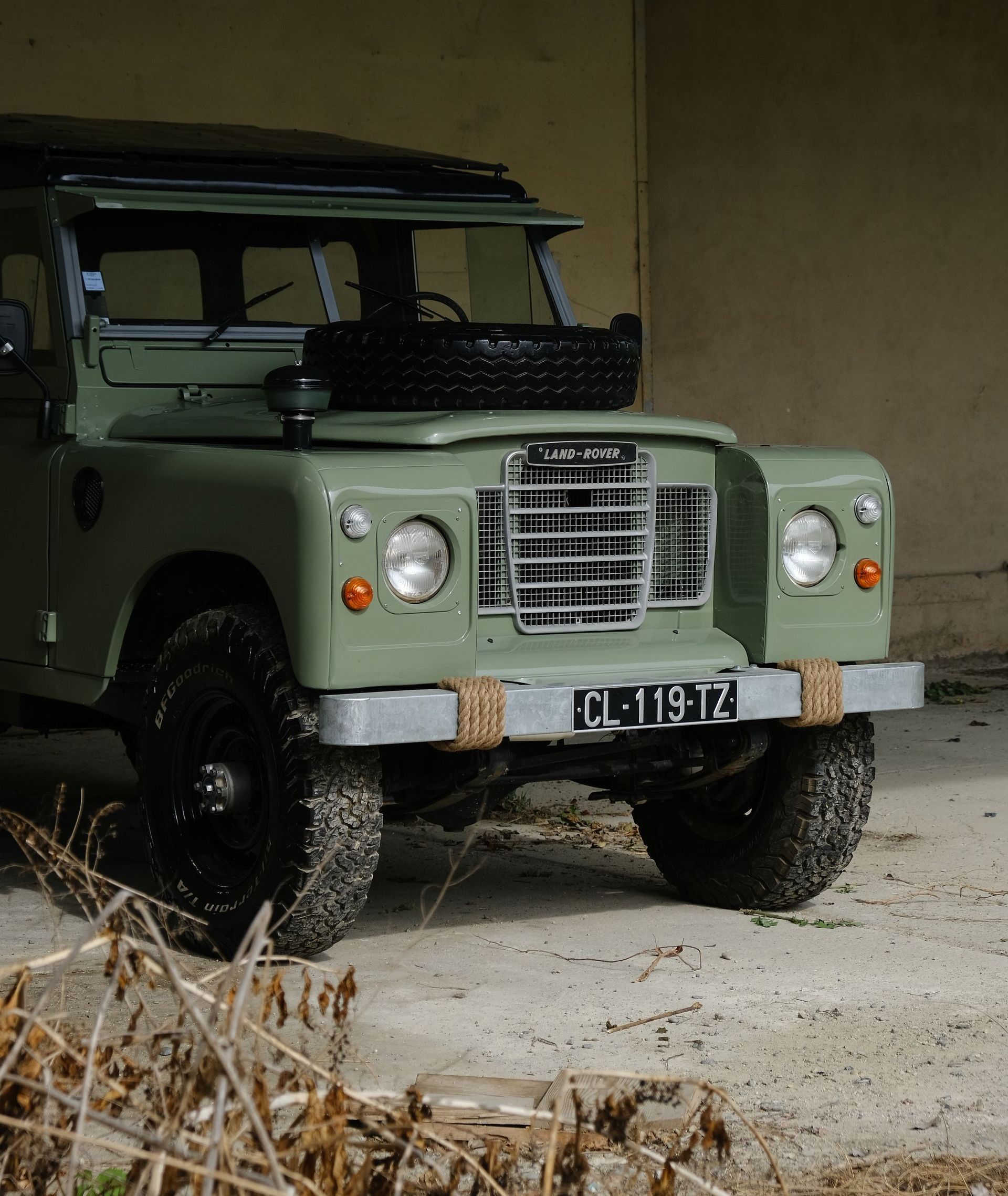 Un SUV Land Rover vert est garé devant un bâtiment beige.