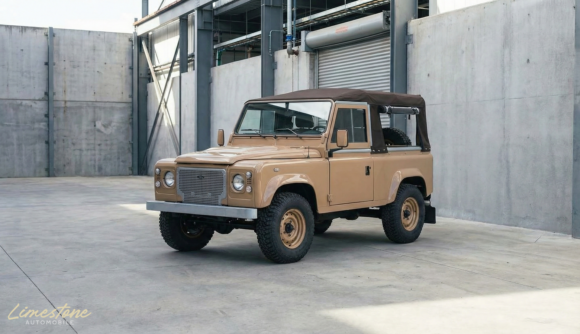 Land Rover Defender beige stationnée dans un environnement industriel en béton.