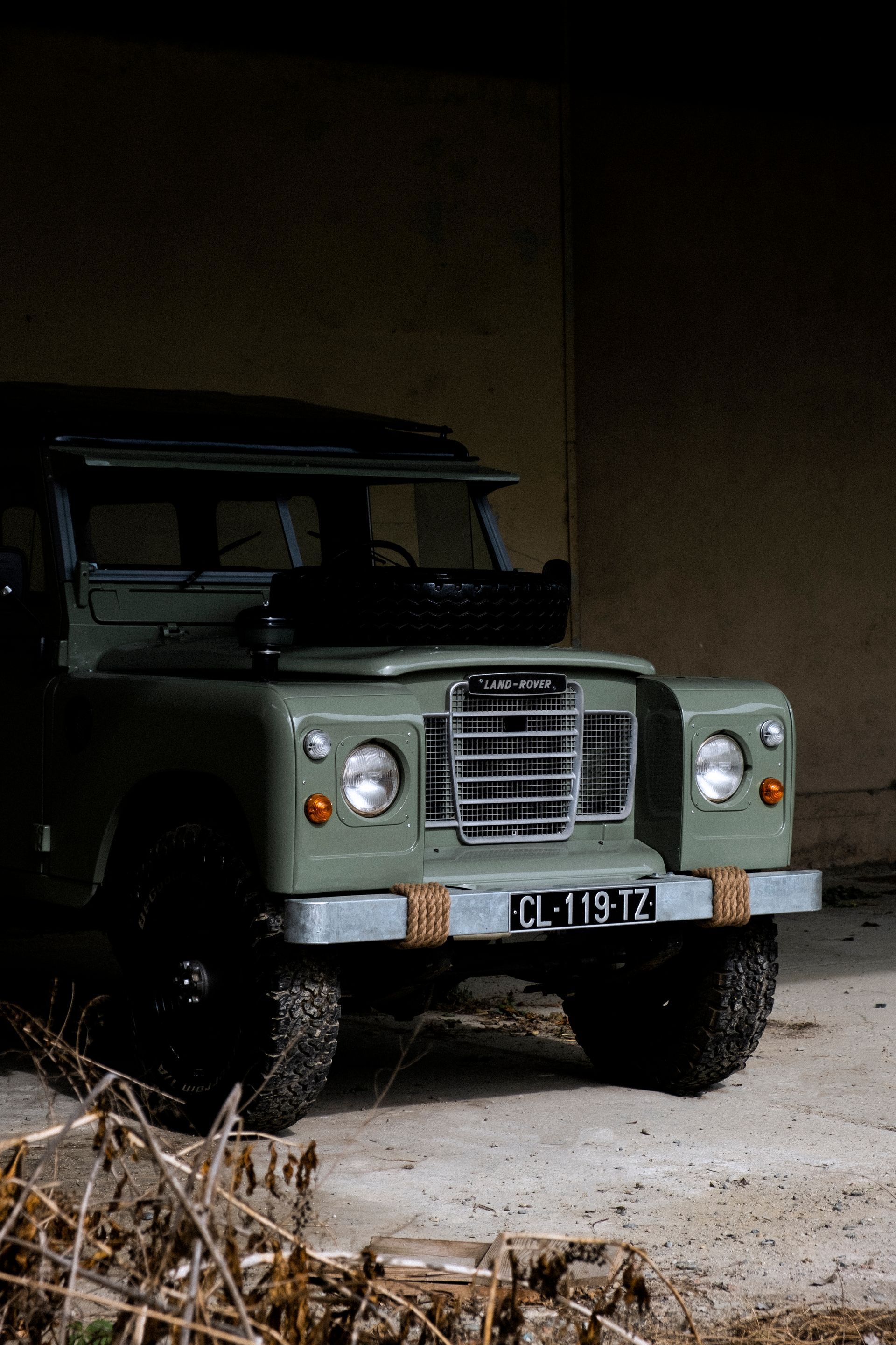 Land Rover verte garée dans un enclos faiblement éclairé, vue de face. Plaque d'immatriculation « CL 1972 ».