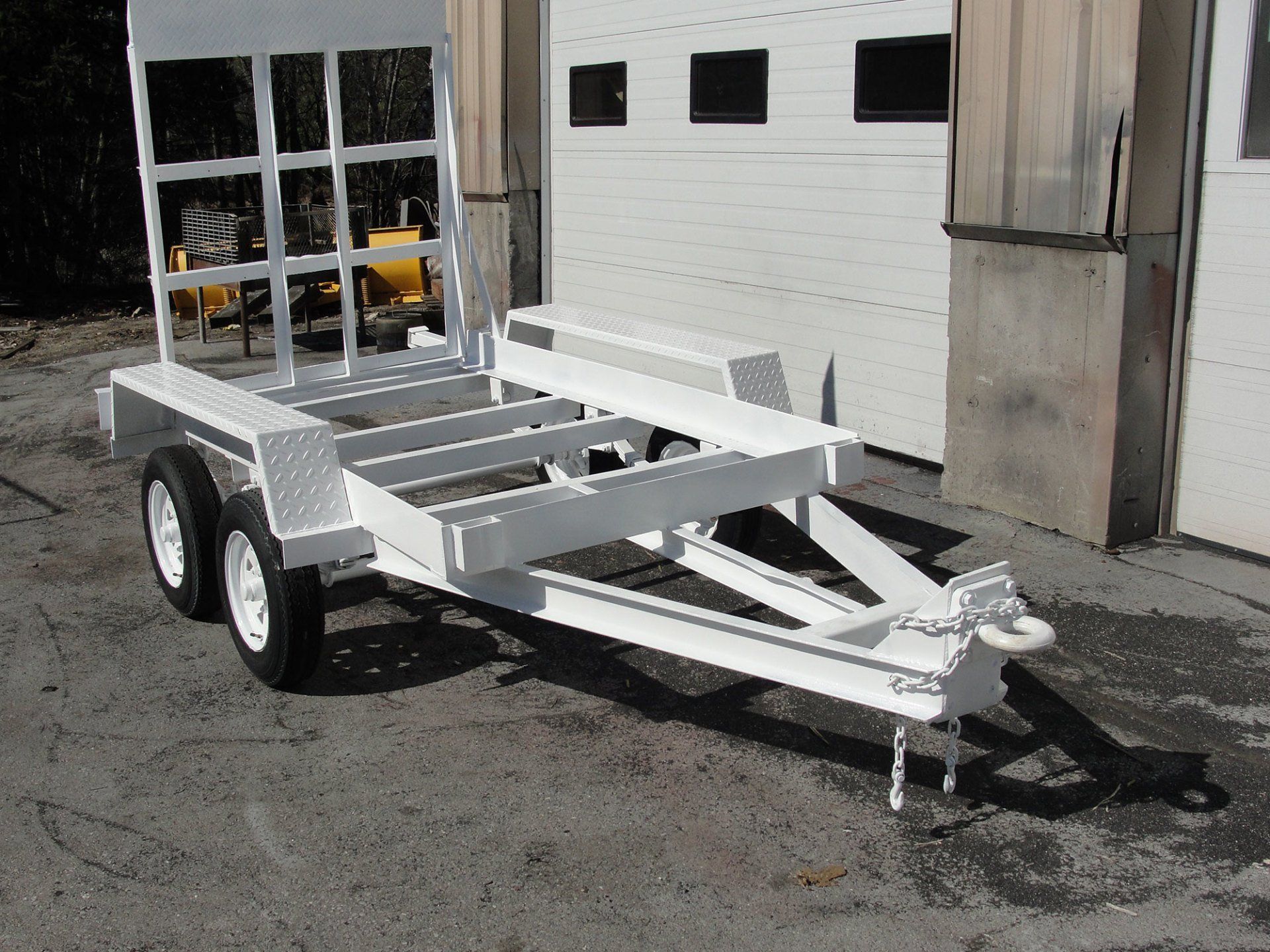 A white trailer is parked in front of a garage door