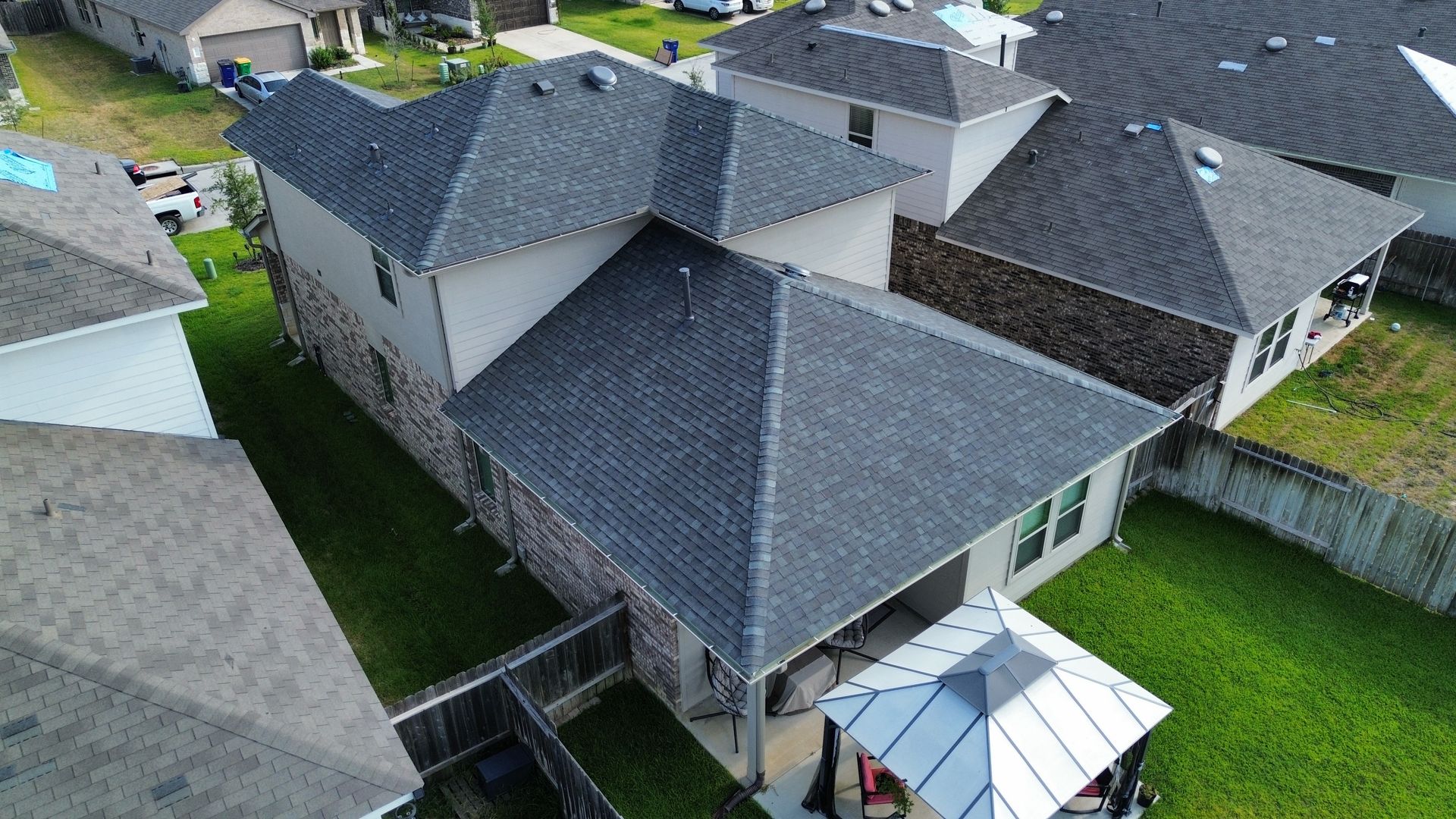 An aerial view of a house with a gray roof in a residential area.