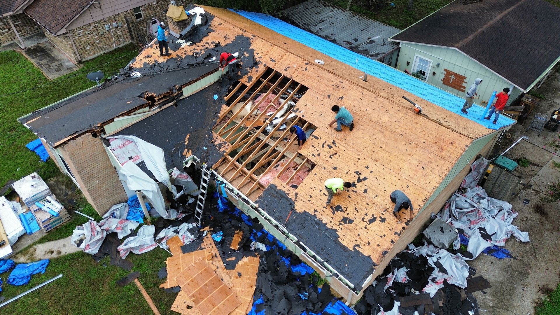 A group of people are working on the roof of a house.
