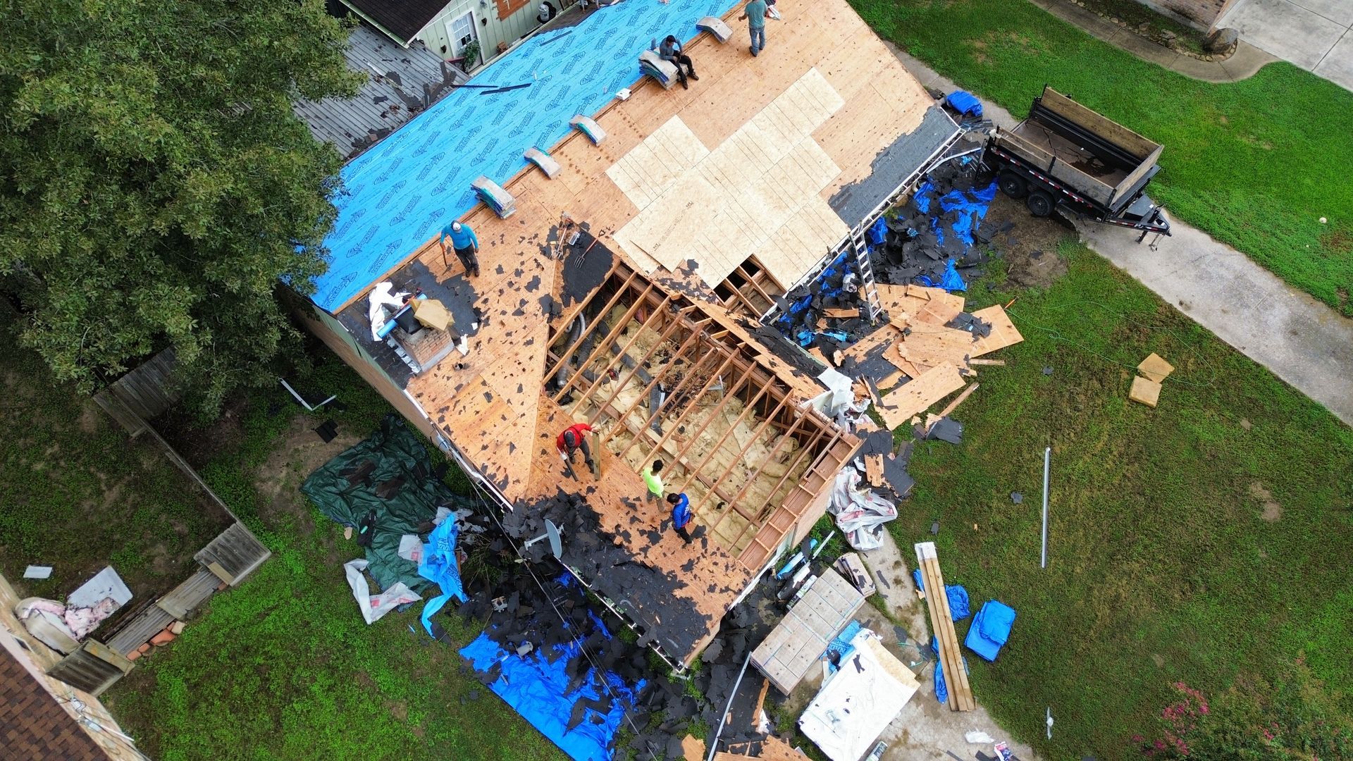 An aerial view of a house being remodeled with a blue roof.
