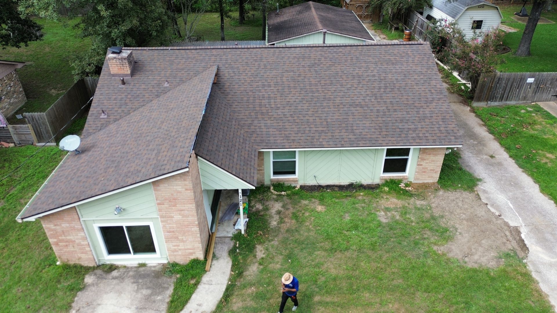 An aerial view of a house with a man standing in front of it.