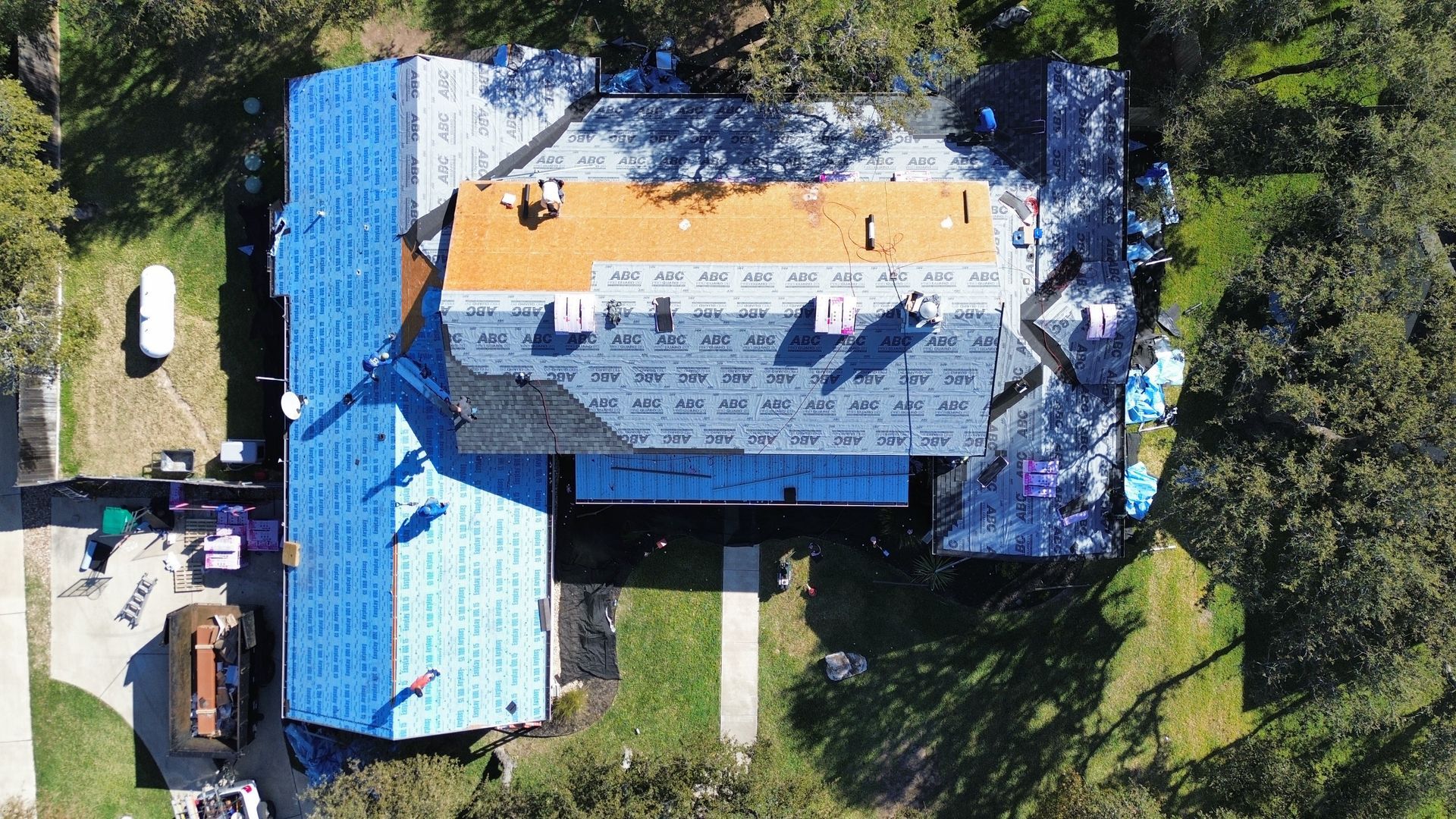 An aerial view of a house under construction with a roof being installed.