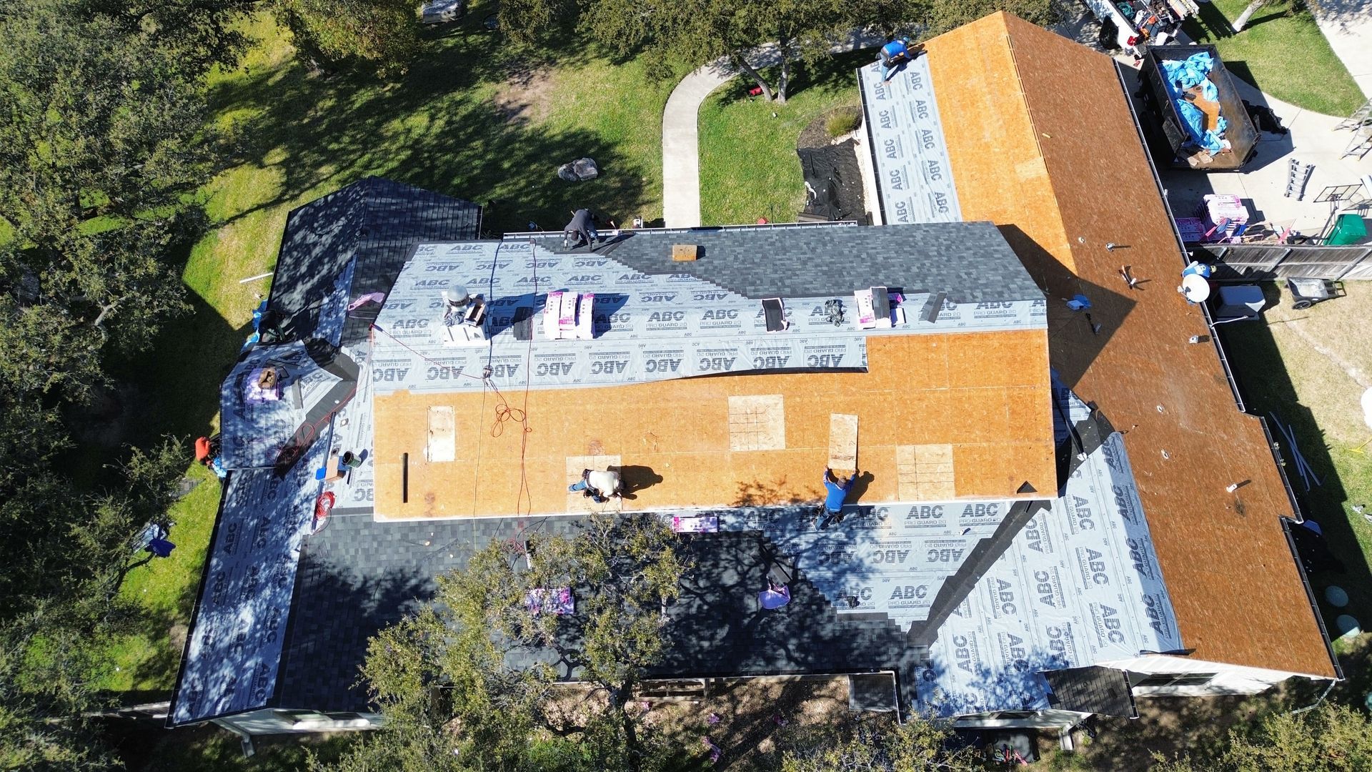 An aerial view of a house under construction with a roof being installed.