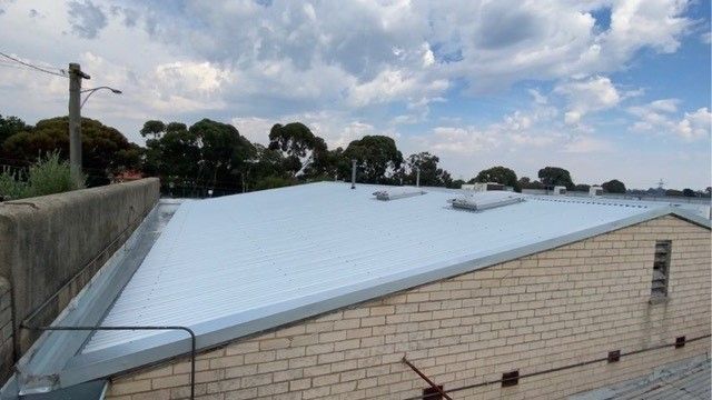 Metal roof on a brick building under a cloudy sky.