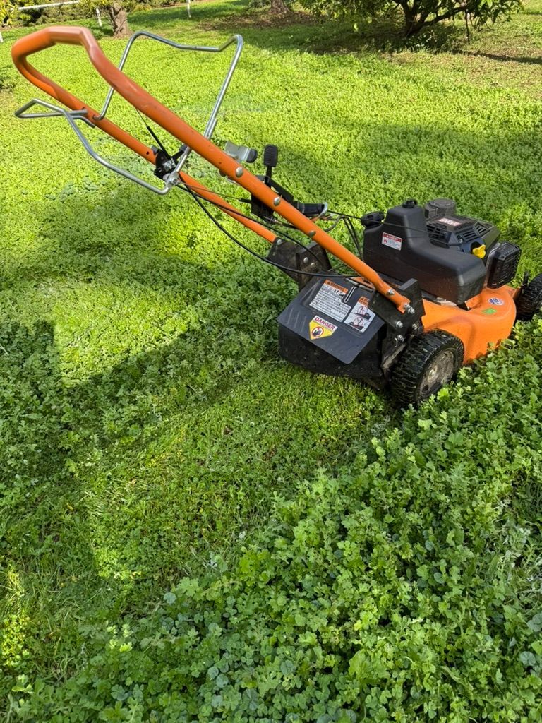 A lawn mower is sitting on top of a lush green lawn.