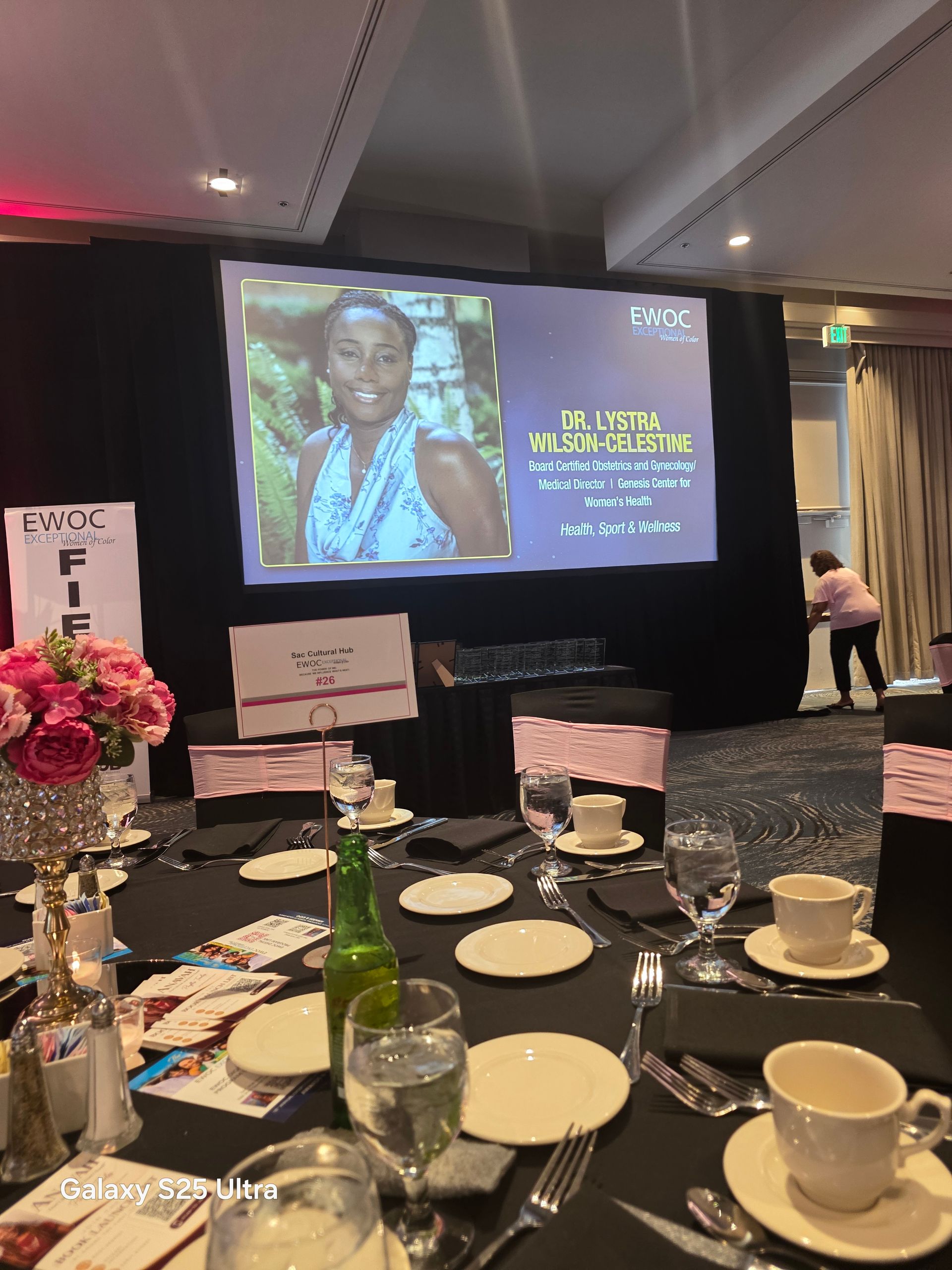 Memorial banquet table facing a large screen with a portrait and tribute text on a lit stage