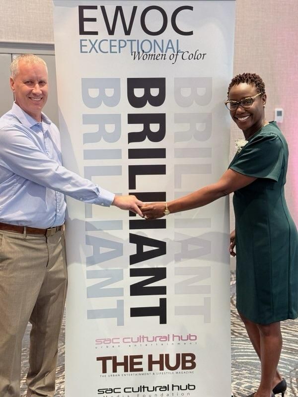 Two people shaking hands in front of an EWOC banner at The Hub