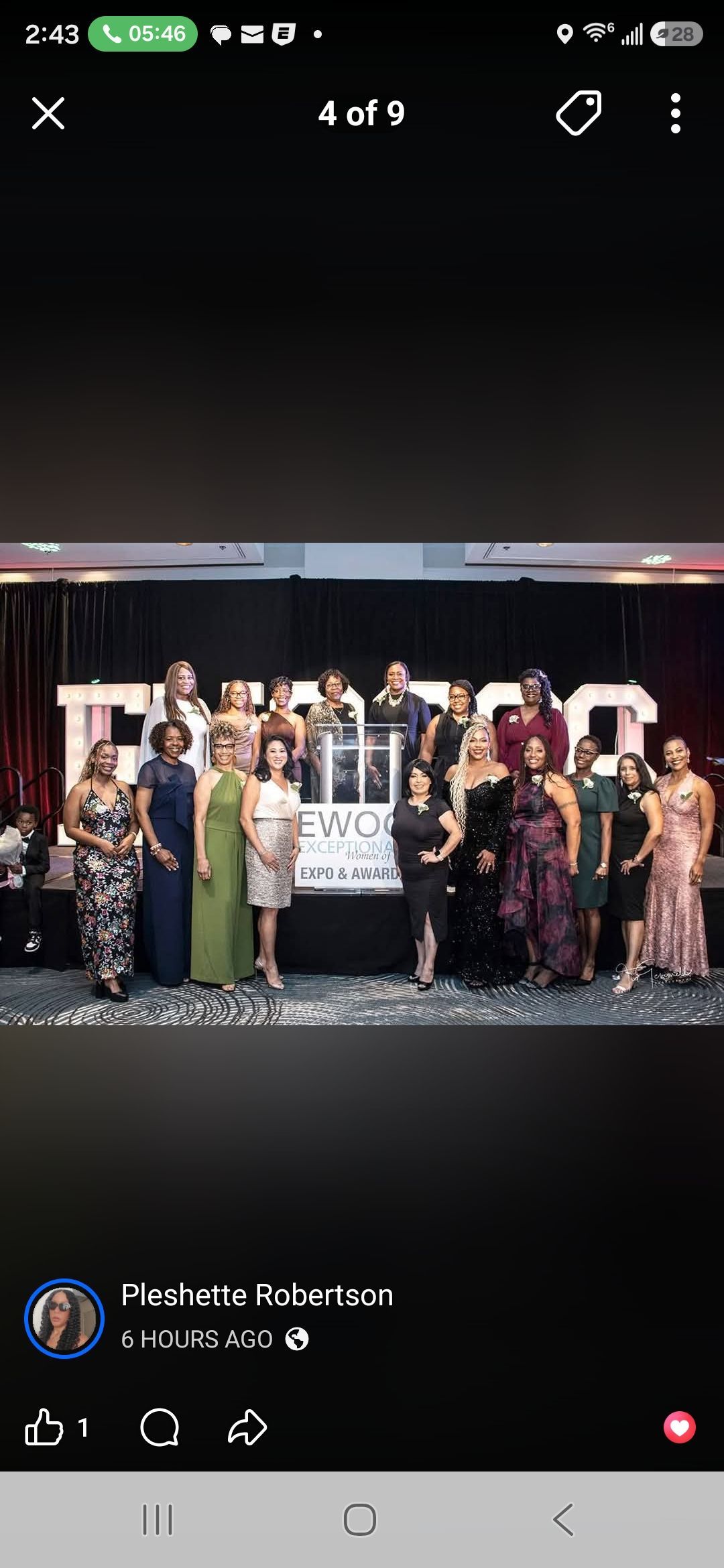 Large group posing on a stage with confetti, holding a framed award during an event celebration.
