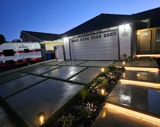 Modern house exterior at dusk with illuminated walkway, garage door, and parked van.
