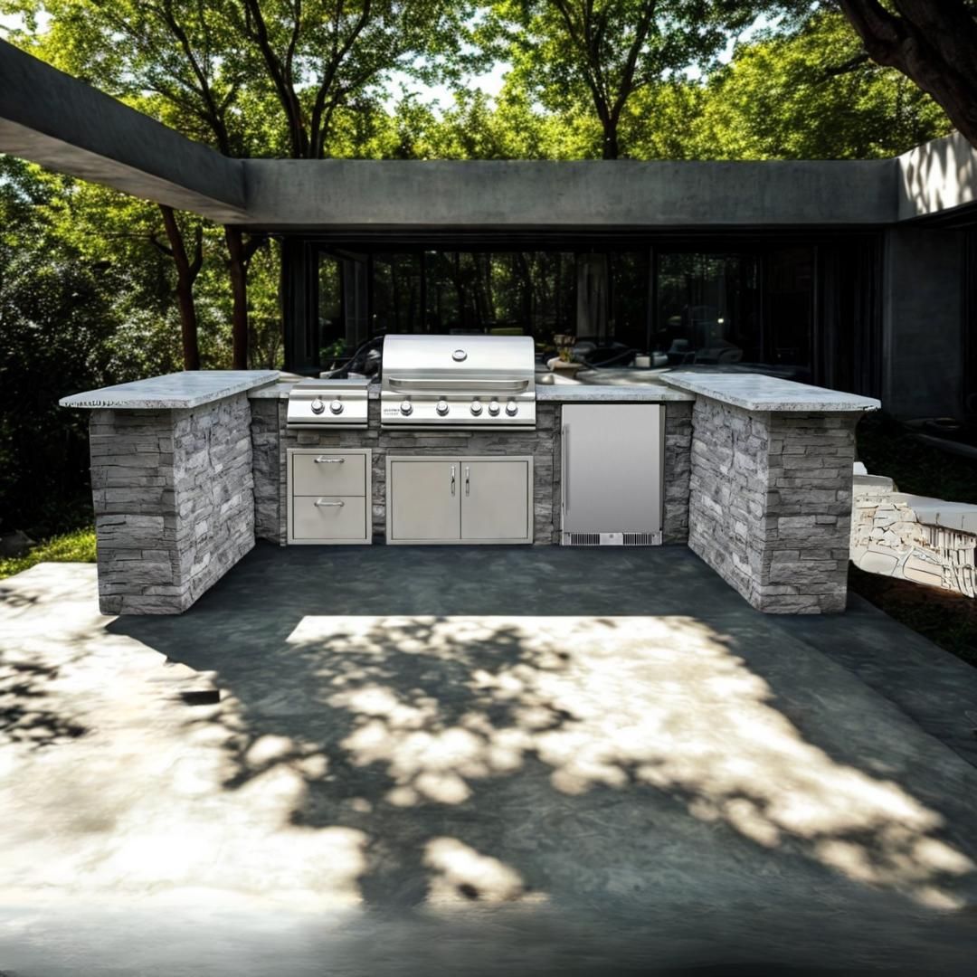 Outdoor stone kitchen with built-in grill and countertops under a shaded pergola, surrounded by trees