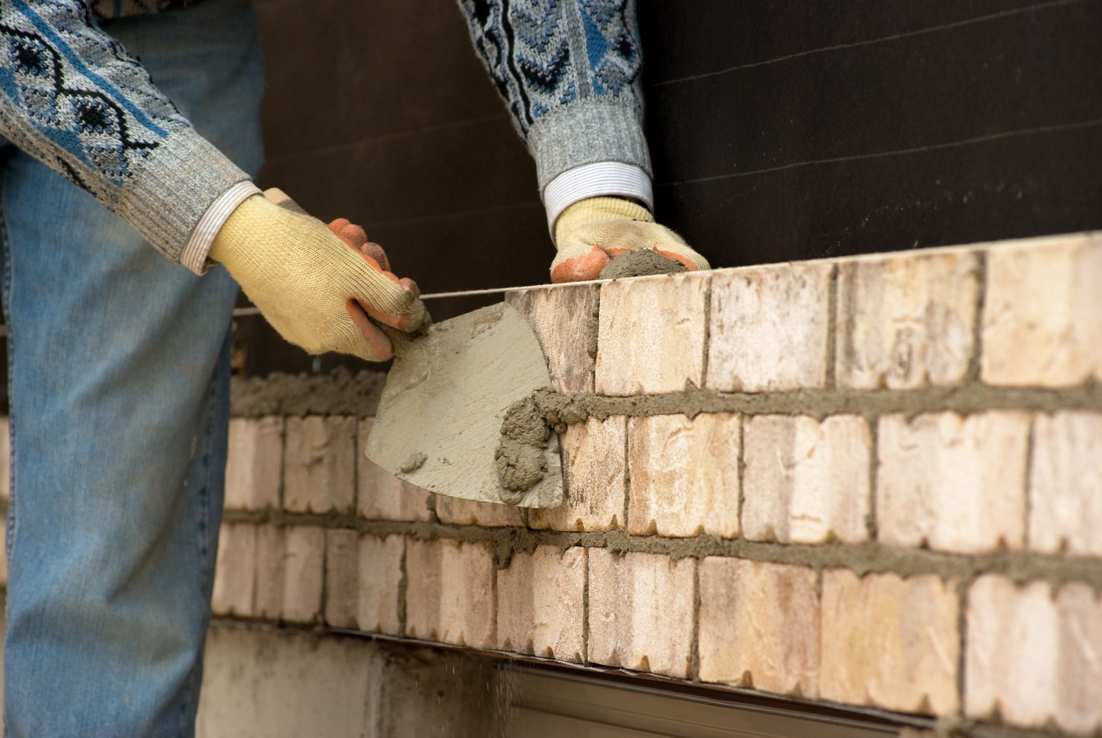 Worker applying mortar to a brick wall during construction
