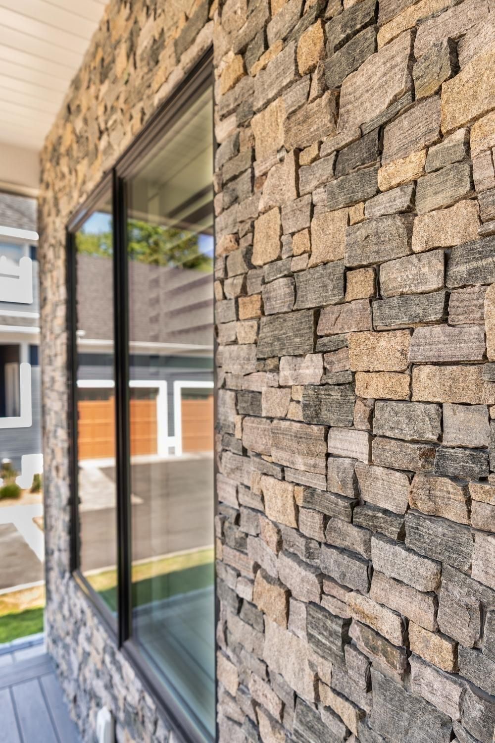 Stone-clad exterior wall with a large window reflecting nearby buildings and greenery