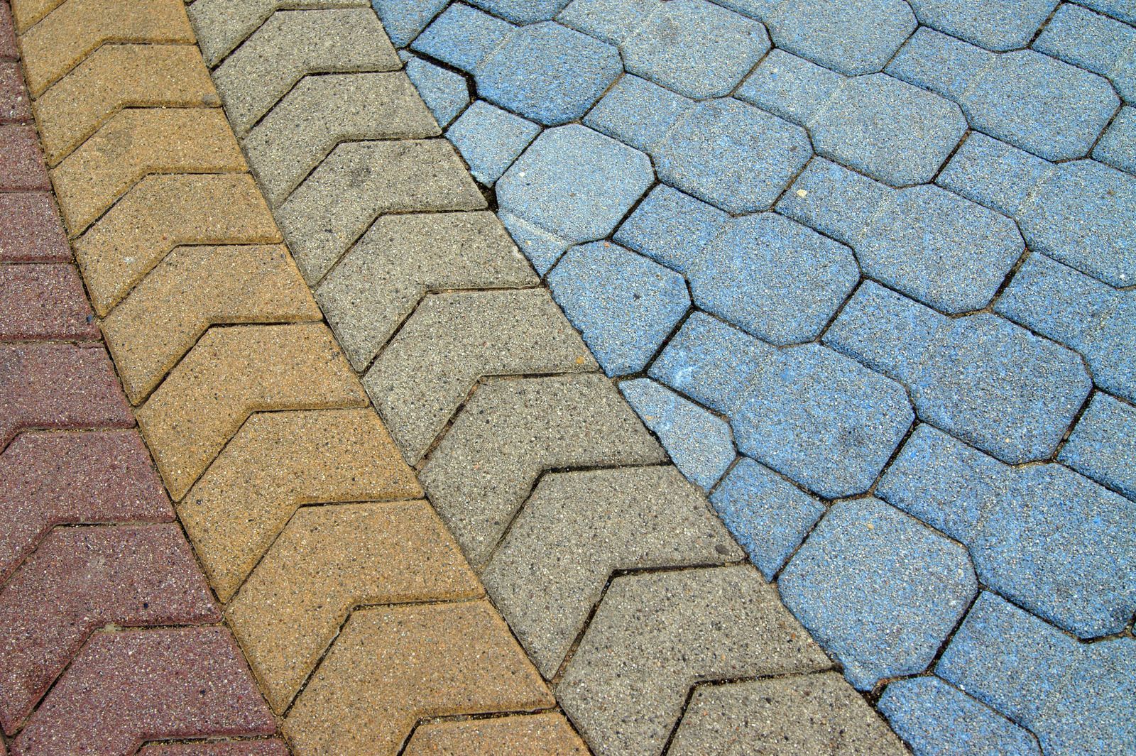 Close-up of overlapping roof shingles in tan, gray, and blue tones