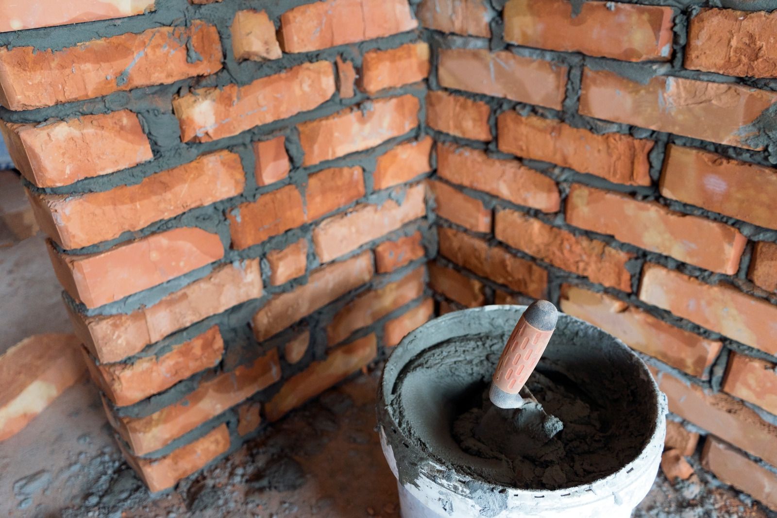 Brick corner with a mortar tub and trowel in a construction site