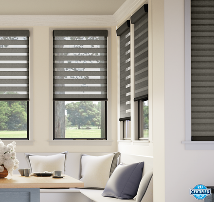 Bright sunroom with gray striped blinds, a window seat, and white and gray cushions.