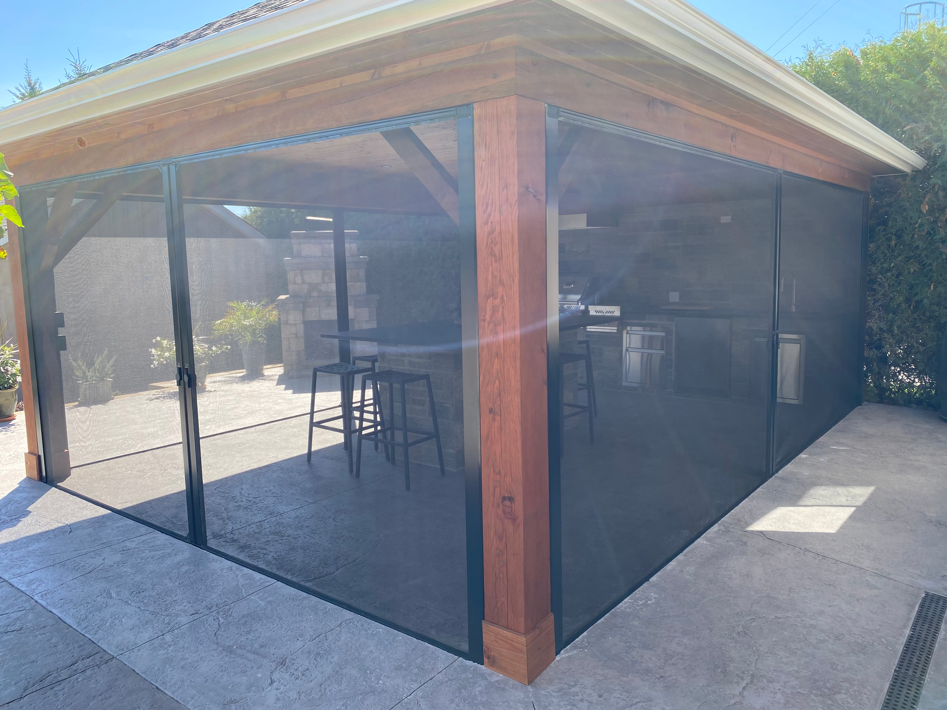 Modern patio with large retractable awning, outdoor sofa and chairs beside a house