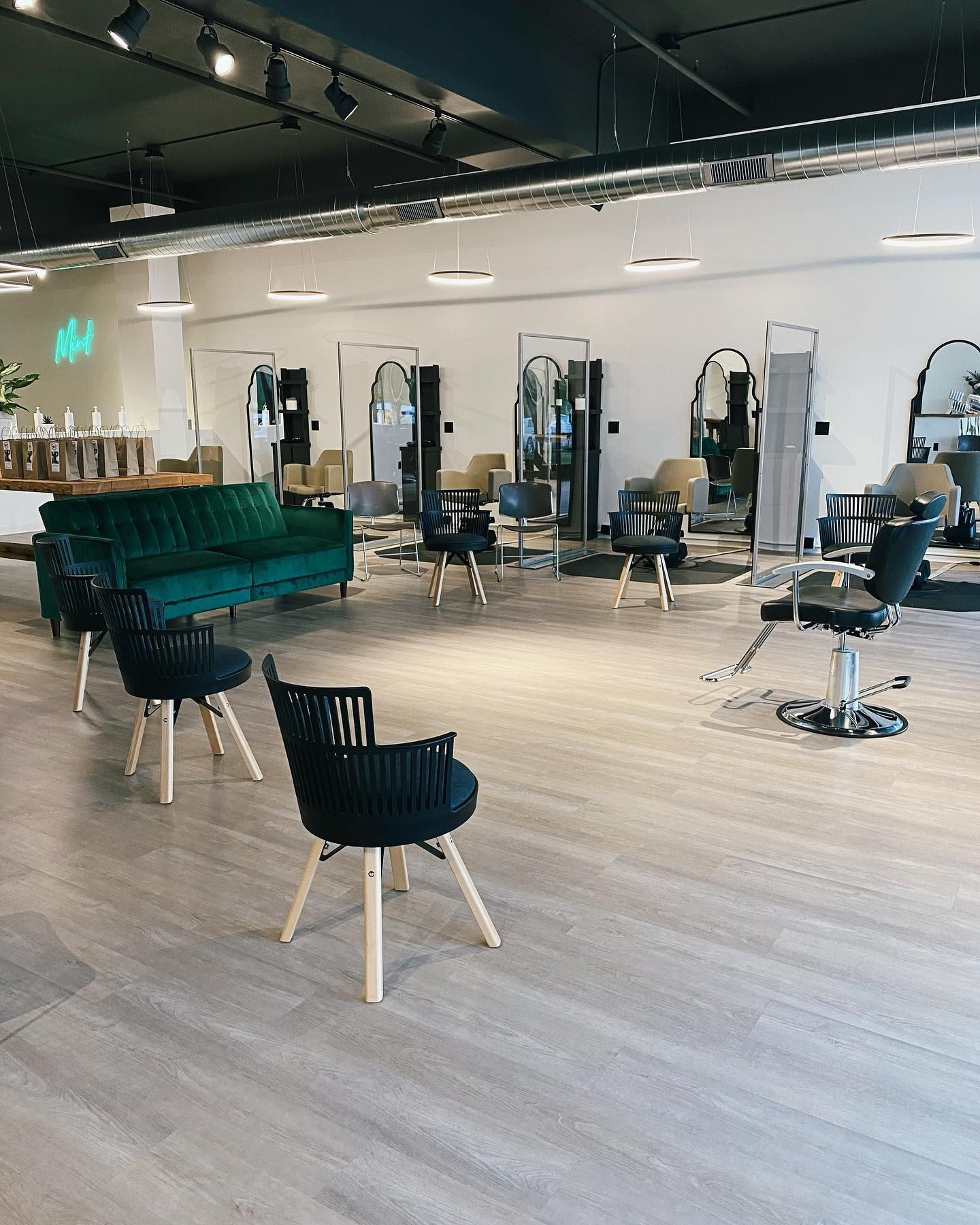A salon with a green couch , chairs , and mirrors.