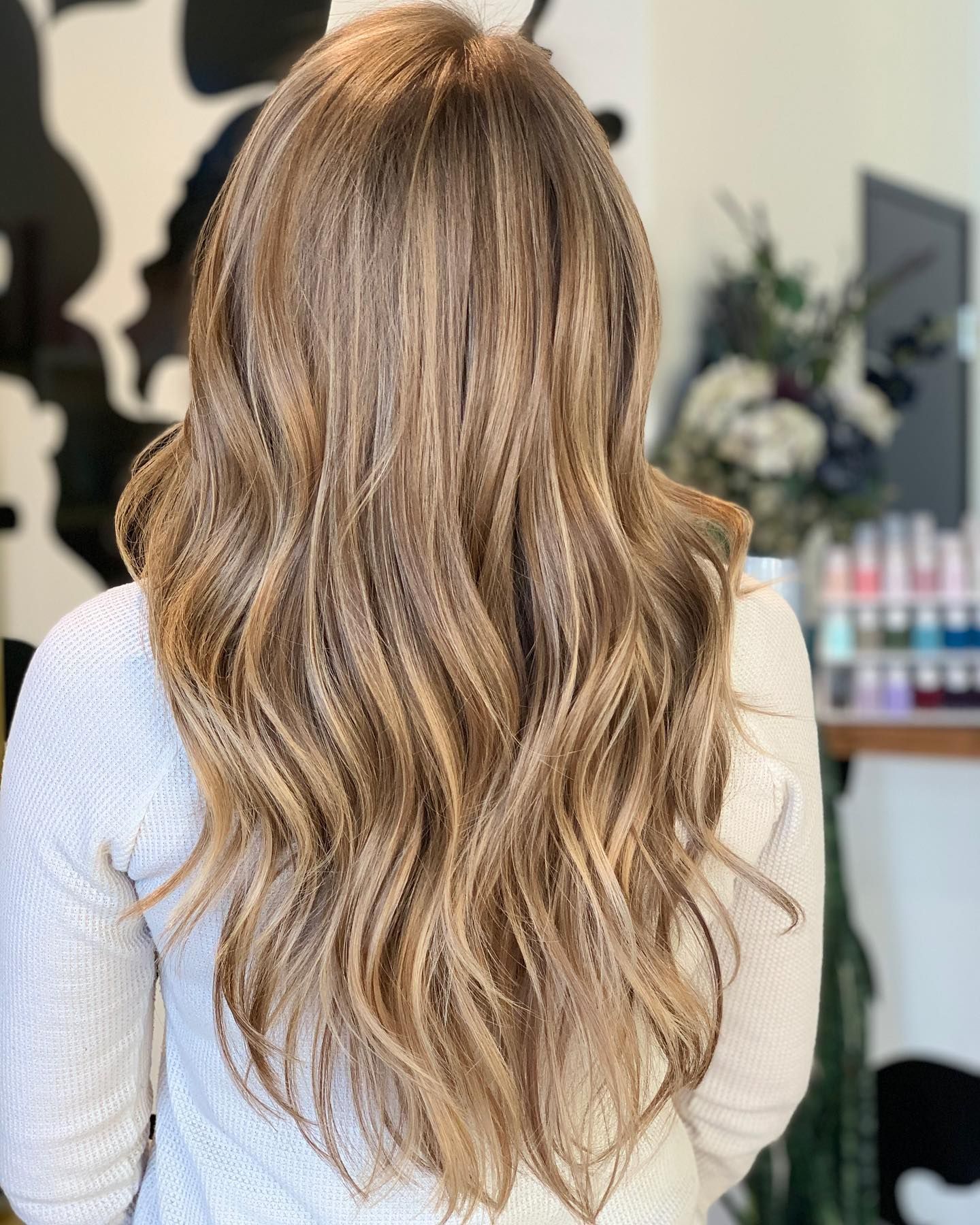 A woman with long blonde hair is wearing a white sweater.