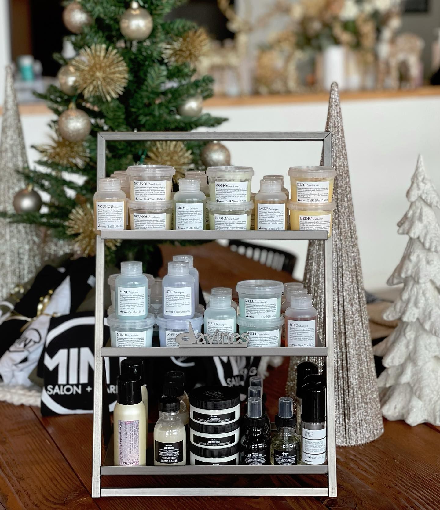 A shelf filled with bottles of cosmetics and a christmas tree in the background