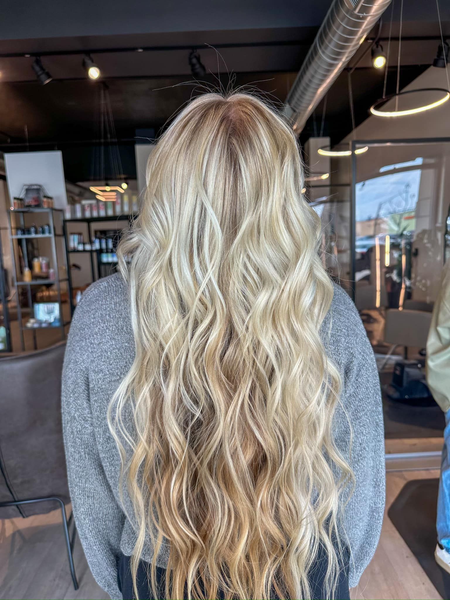 A woman with long blonde hair is standing in a salon.