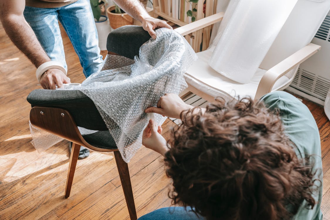 couple covering a chair with bubble wrap
