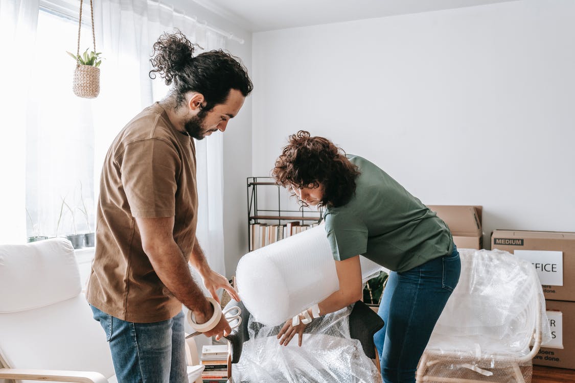couple covering a chair with bubble wrap