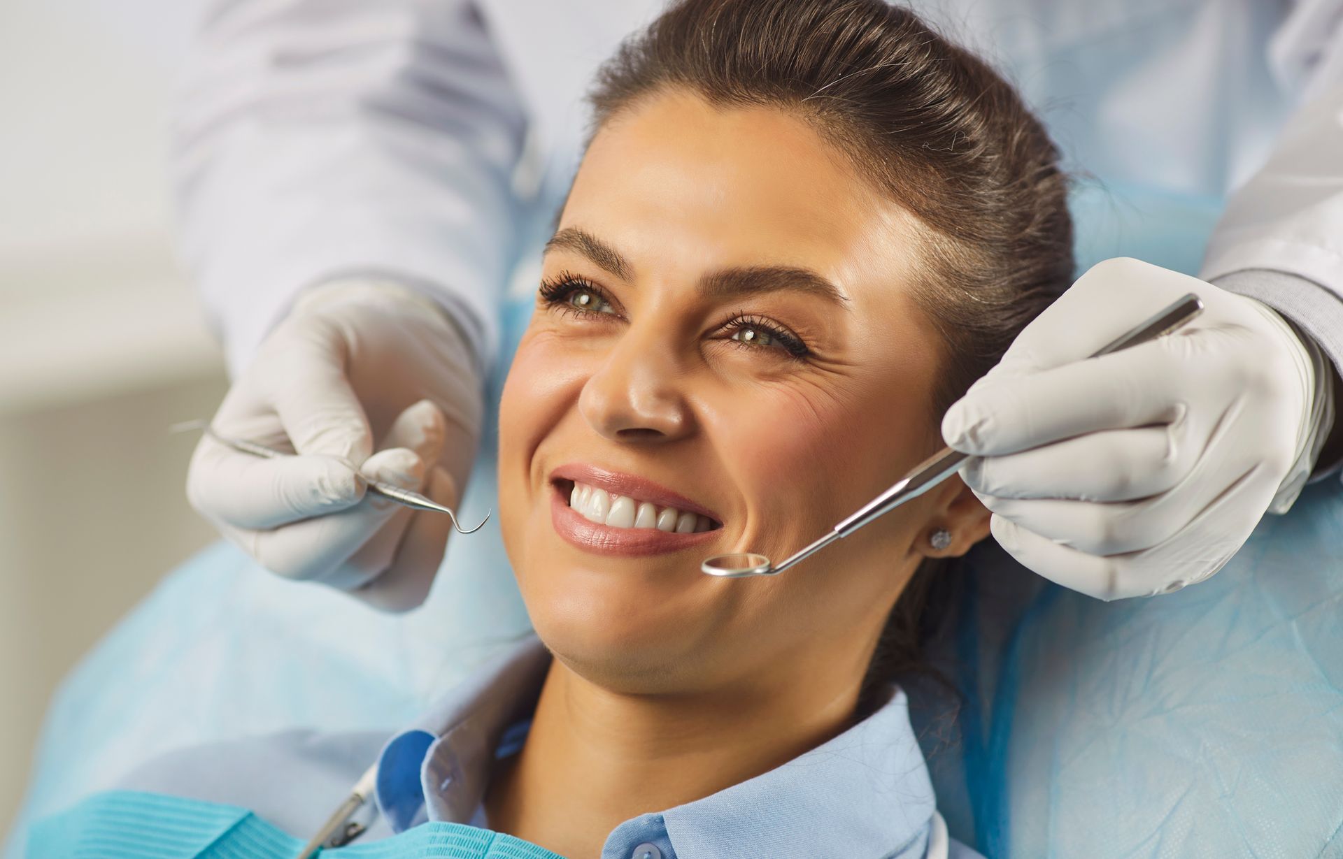 Smiling dental patient in chair while dentist adjusts braces with gloved hands Smiling dental patient in chair while dentist adjusts braces with gloved hands