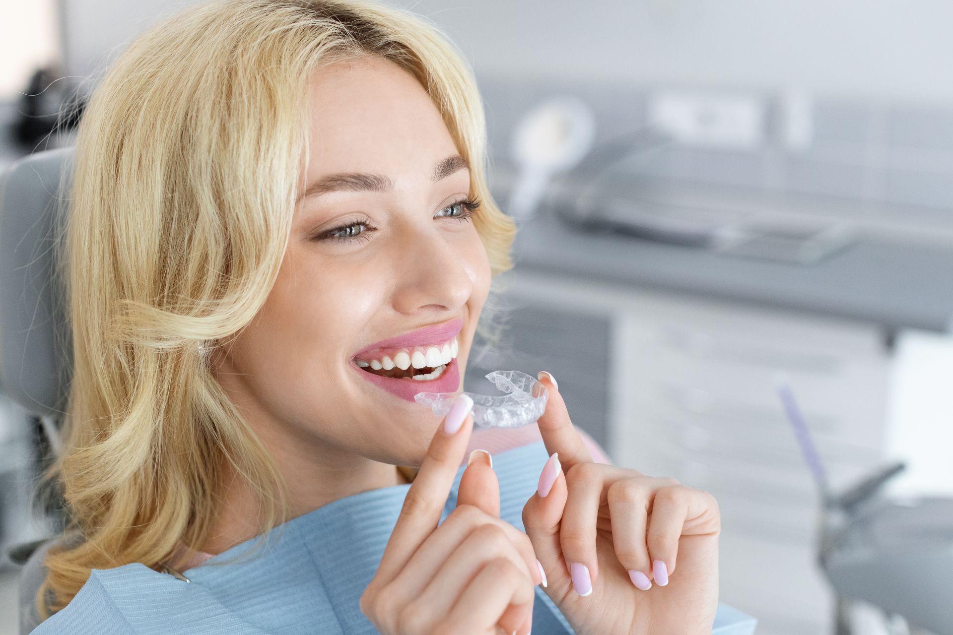 Smiling woman holding clear aligner in a bright dental clinic Smiling woman holding clear aligner in a bright dental clinic
