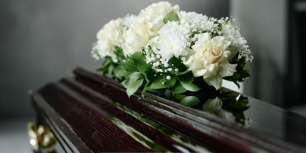 White floral arrangement placed on a wooden casket during a service at a funeral home and cremation service in Hanover, PA.