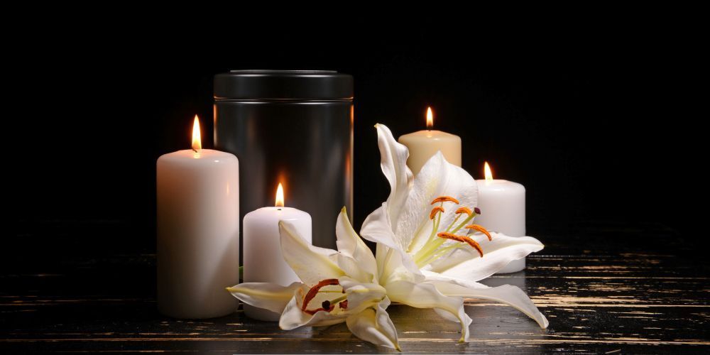 Memorial candles and white lily flowers beside an urn representing a funeral home and cremation service in Hanover, PA.