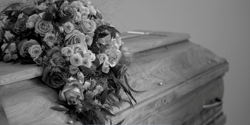 Bouquet of roses placed on a wooden casket during a memorial service at a funeral home and cremation service in McSherrystown, PA