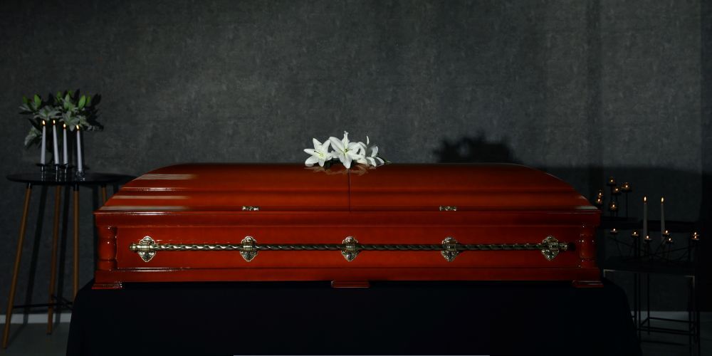Polished wooden casket with white lilies and candles during a memorial ceremony at a funeral home and cremation service in McSherrystown, PA