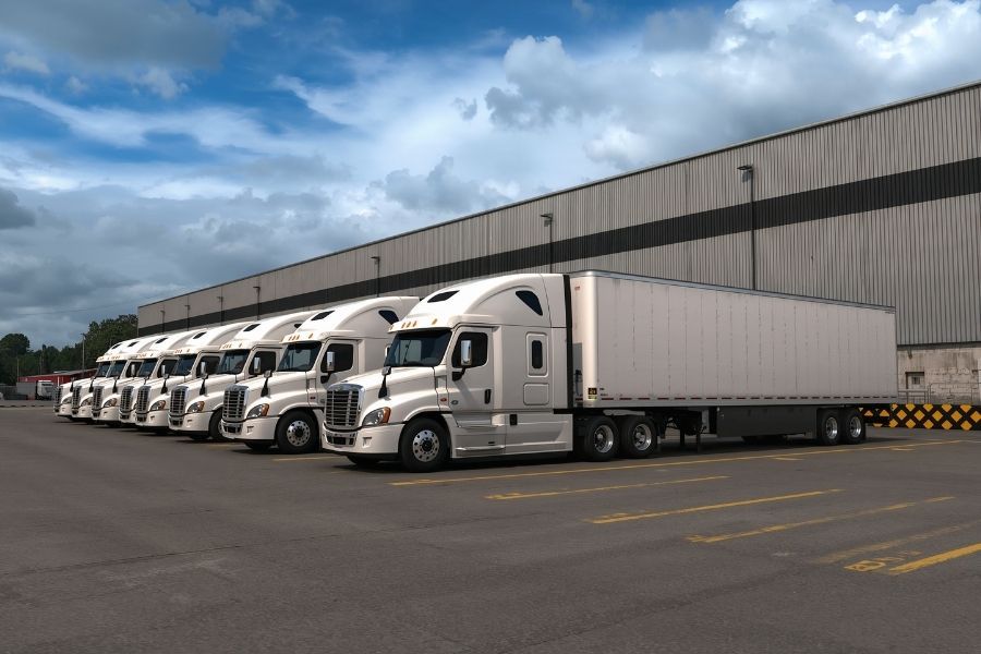 Row of commercial trucks and trailers parked in a fleet yard