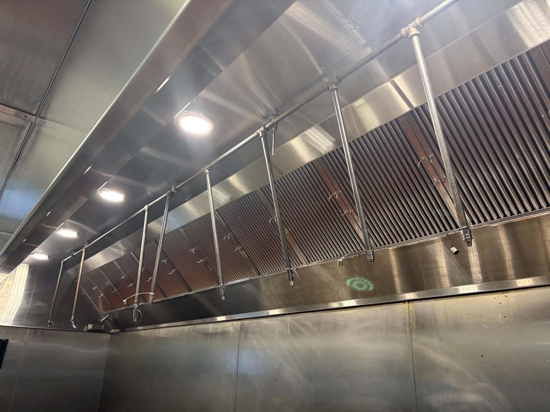 Clean stainless steel baffle filters seated edge to edge in a commercial kitchen exhaust hood with no gaps between them