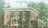 Brick Victorian house with white trim, a turret, and climbing ivy.