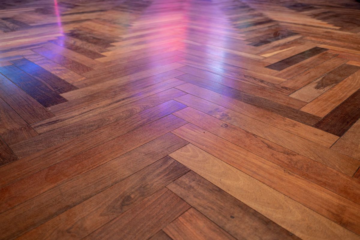 A close up of a wooden floor with a herringbone pattern.