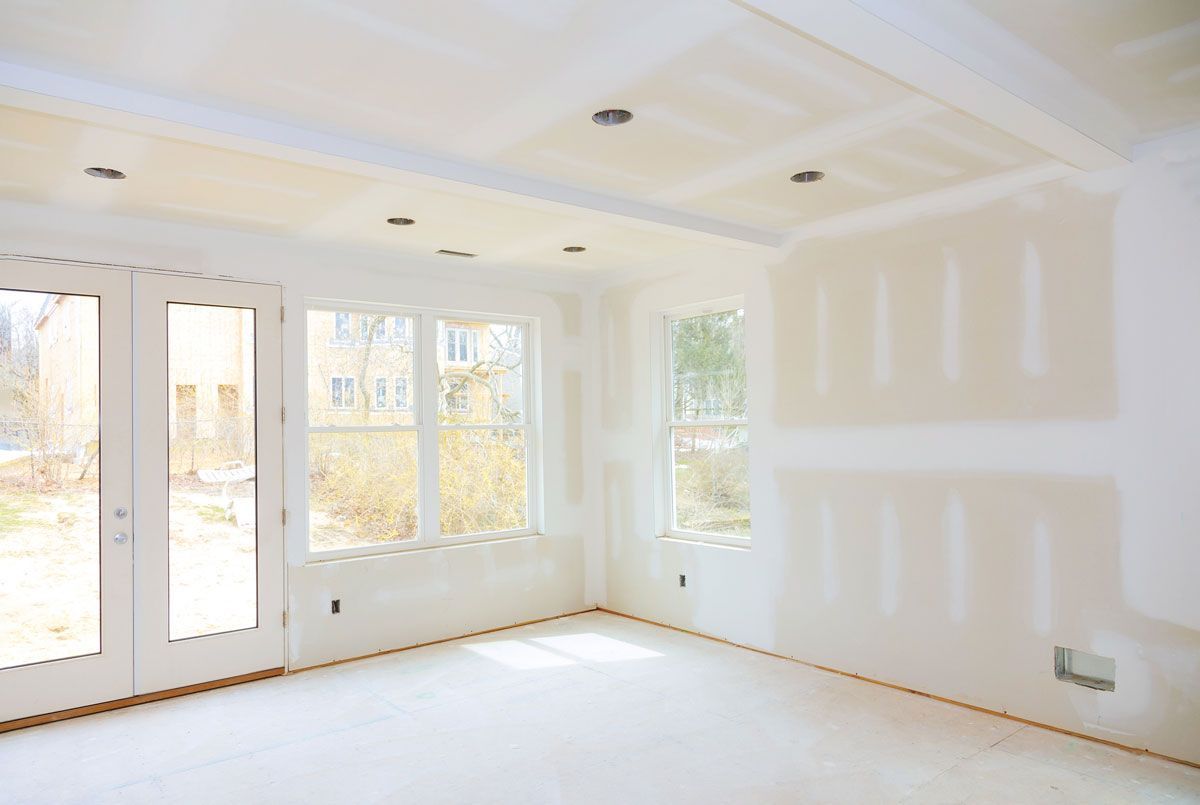 An empty room with a lot of windows and drywall on the walls.
