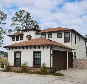 Two-story beige house with brown roof and garage, viewed from the driveway