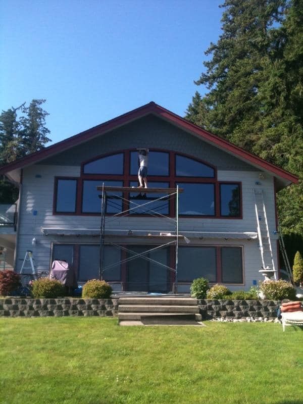 House facade with a worker on scaffolding under a blue sky