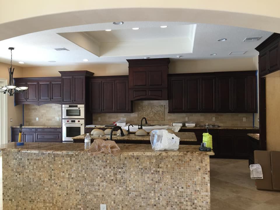 Large modern kitchen with dark cabinets, granite island, and stacked boxes on the counter