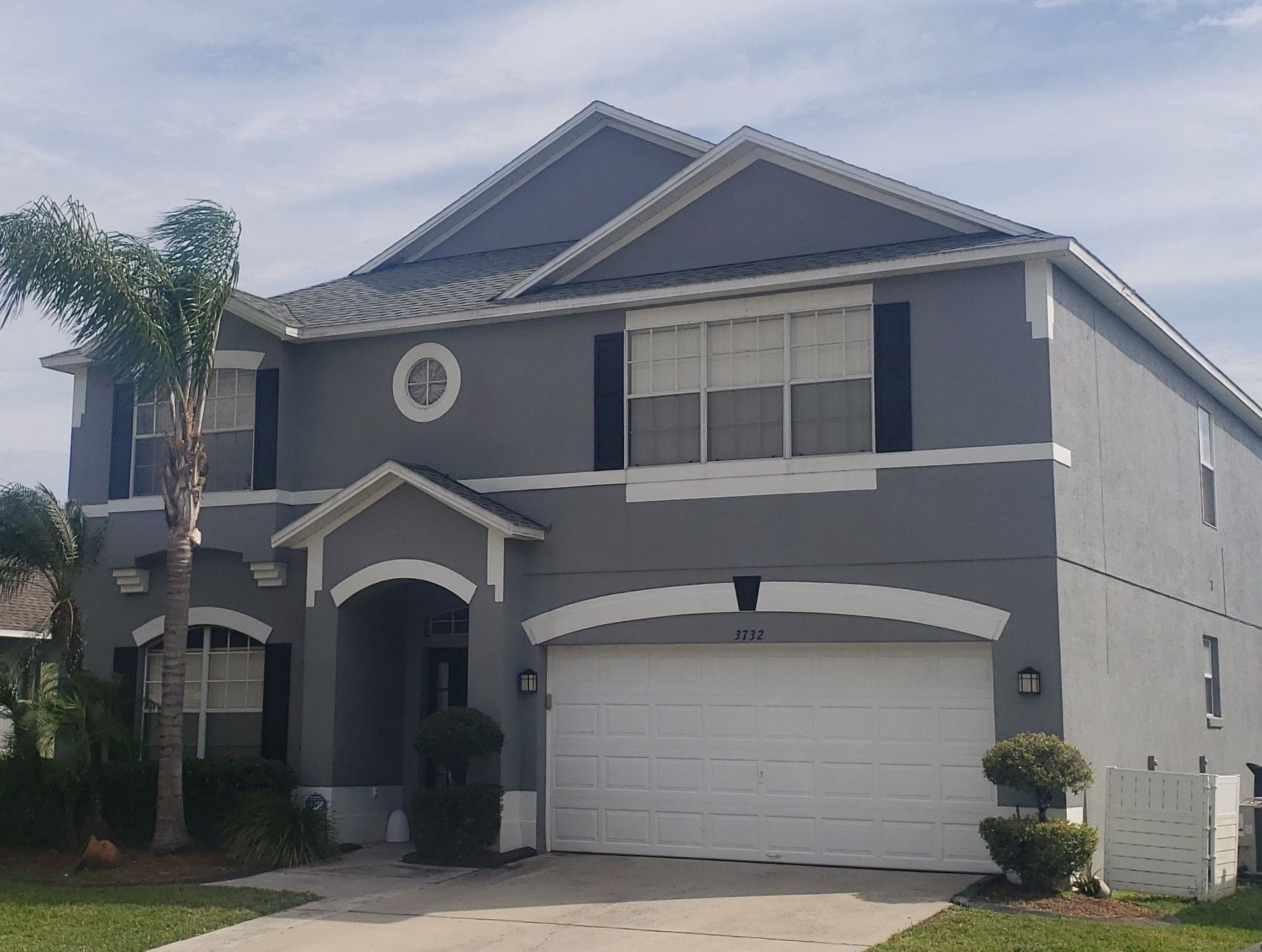 Two-story gray suburban house with white garage and trimmed front yard
