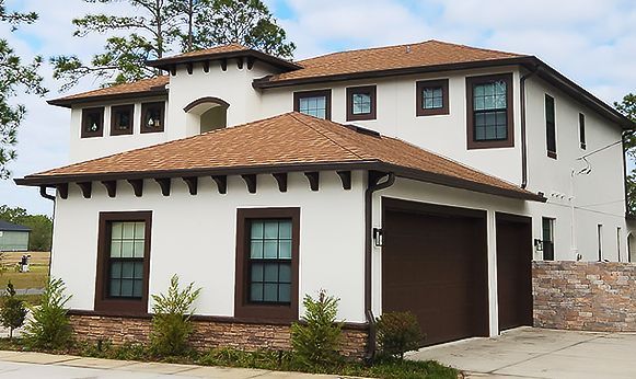 Two-story white stucco house with brown roof, dark trim, and a covered front porch.
