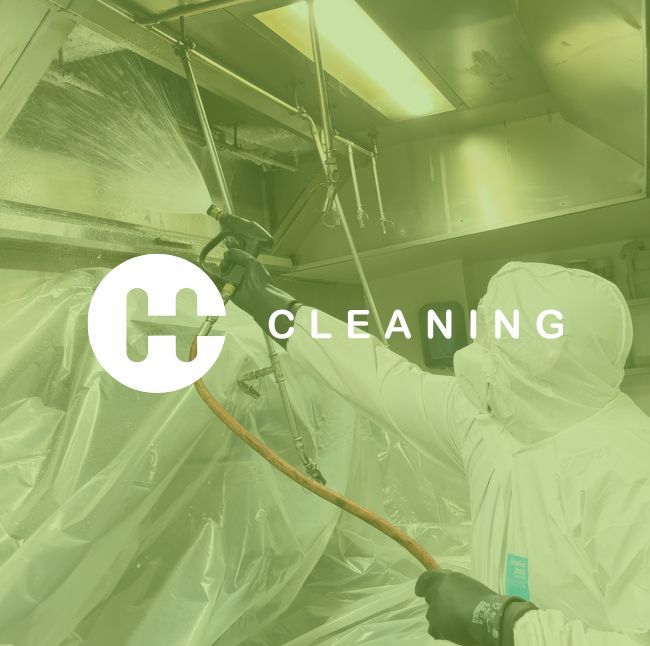 Person in protective suit cleaning with a spray gun in a commercial kitchen setting.