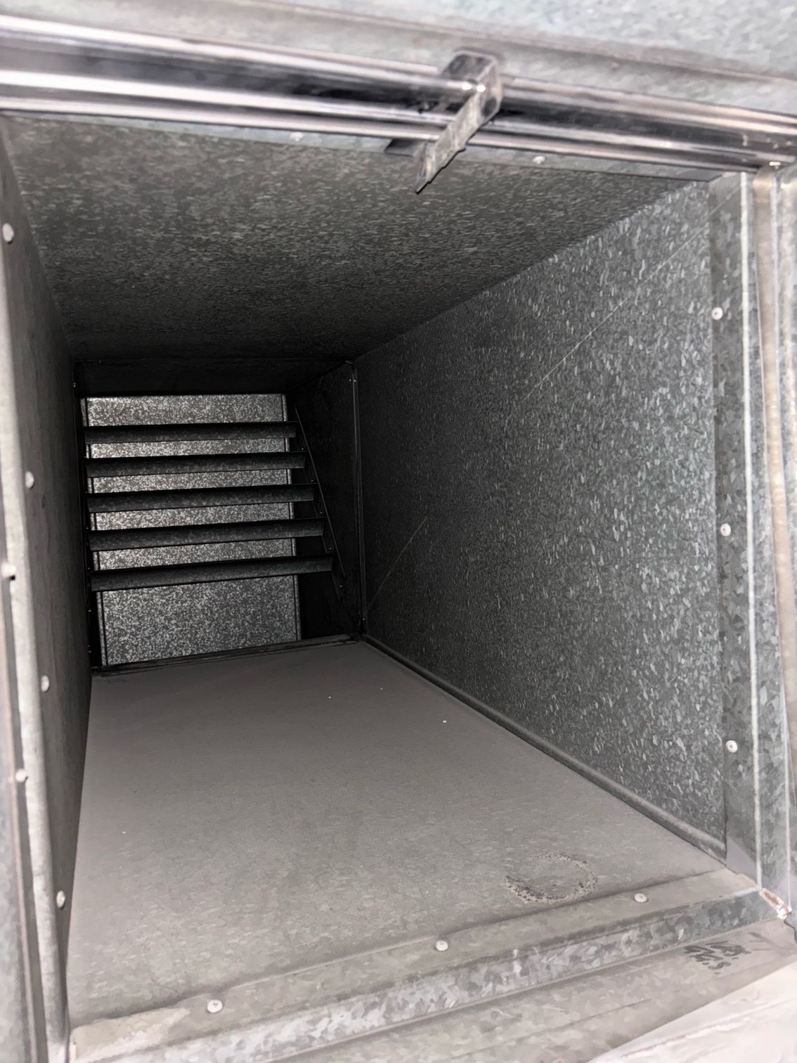 Rectangular metal HVAC duct interior; gray, with visible filters.