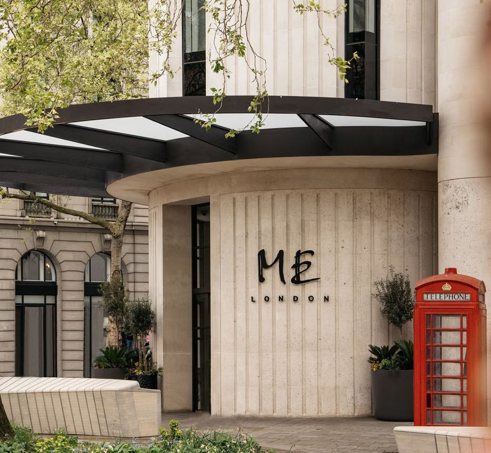 Entrance to the ME London hotel. Cream-colored exterior with black awning, red phone booth, and