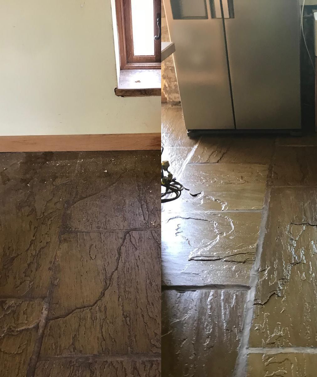 Damaged floor with cracked stone tiles next to a doorway and stainless steel refrigerator.