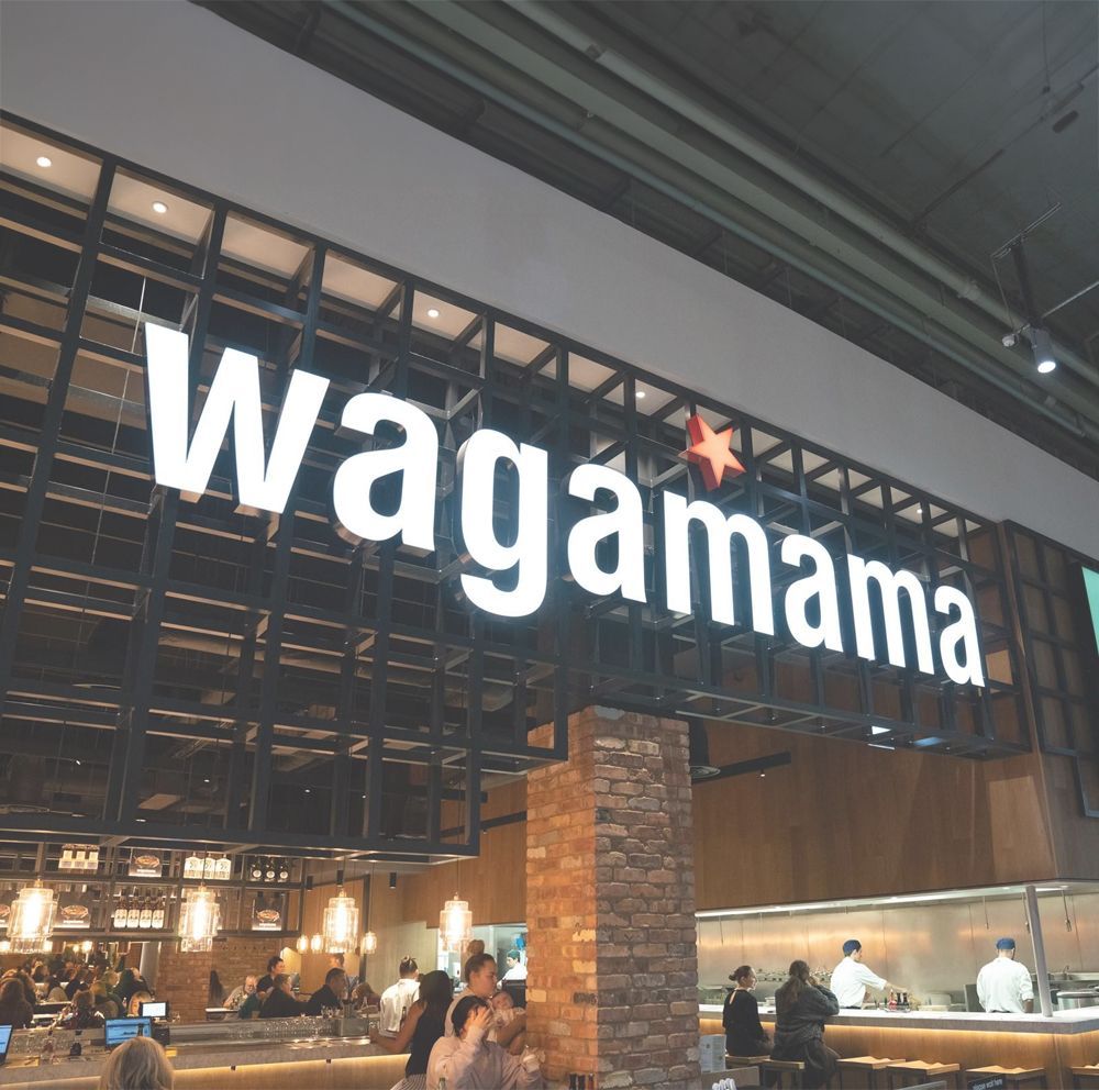 Wagamama restaurant sign with customers and staff inside.